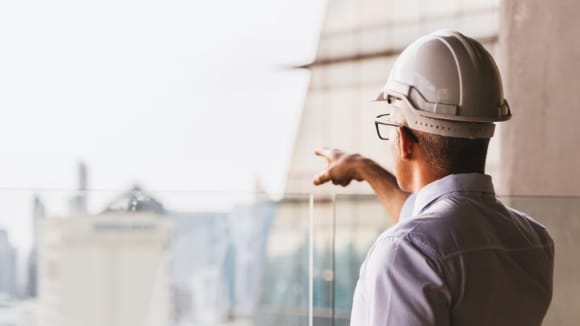 Man in hardhat pointing out to city skyline