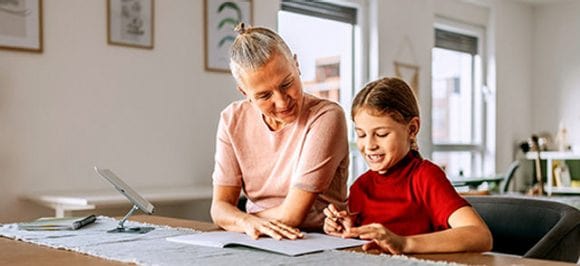 Dame âgée aidant un enfant à étudier à la maison.