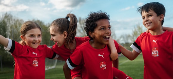 L’image montre des enfants en liesse sur un terrain de football.