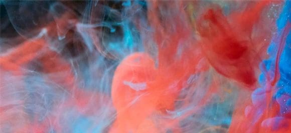 L'image montre des liquides rouges et bleus se mélangeant dans l'eau pour créer des motifs et des dégradés de couleurs fascinants – une composition artistique et dynamique.