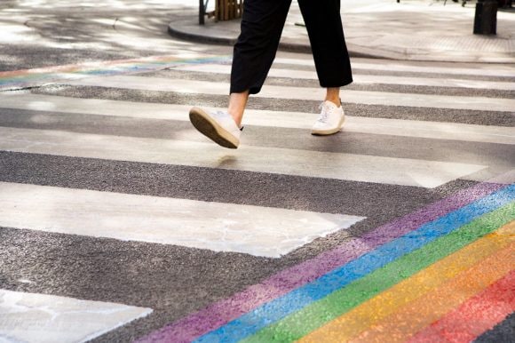 Pedestrian walking over zebra crossing with pride colors
