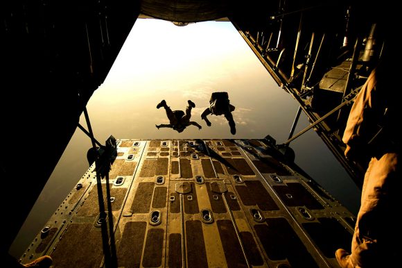 Two members of the military diving out of a plane.
