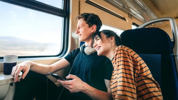 Couple sitting inside a train near a window