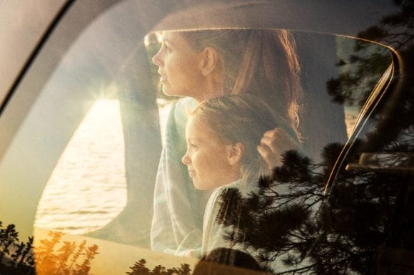 A woman and young girl are seen through the window of a car