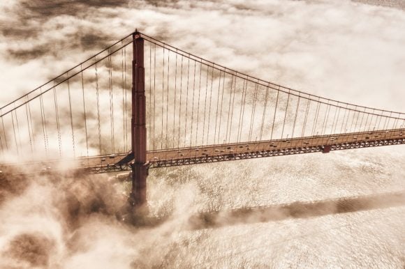 A suspension bridge, partially enveloped in thick fog