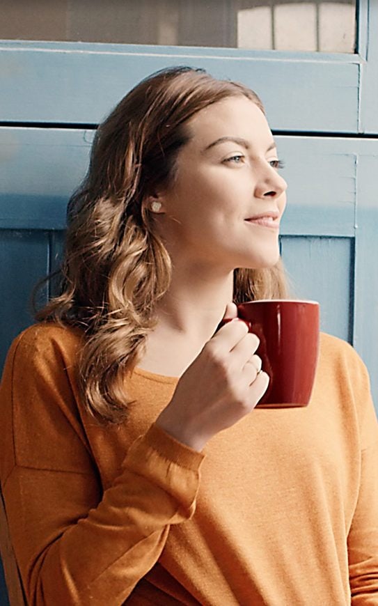 Woman relaxing with a cup of coffee on her balcony