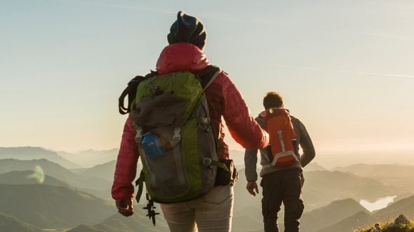 View of two people hiking in the mountains with the morning sun