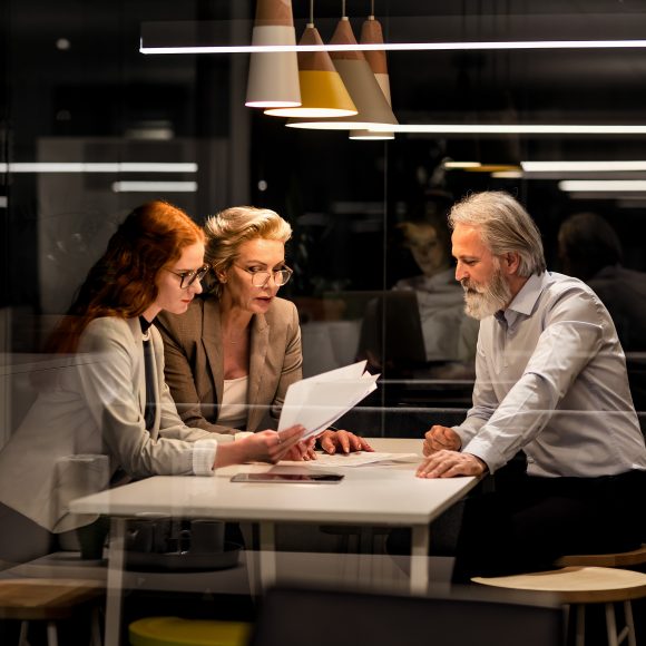 Three people in a meeting room and going through documents