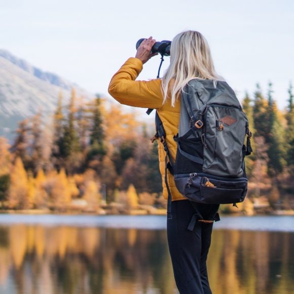 Woman hiker looking at mountain, using binoculars