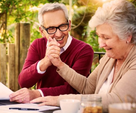 Une femme et un homme sont assis devant des documents et se serrent la main avec joie.