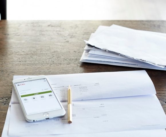 A smartphone with the UBS app open lies on top of an opened letter.