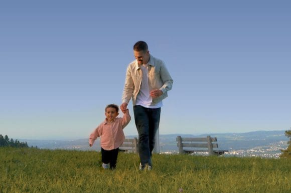 Vater und Töchterchen laufen fröhlich über eine Bergwiese
