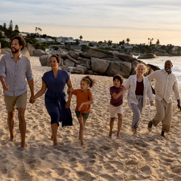 Three generations of a family walk along the beach.