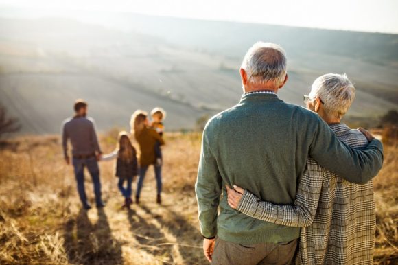 Grandparents look at their daughter’s family with two children hiking in the mountains.