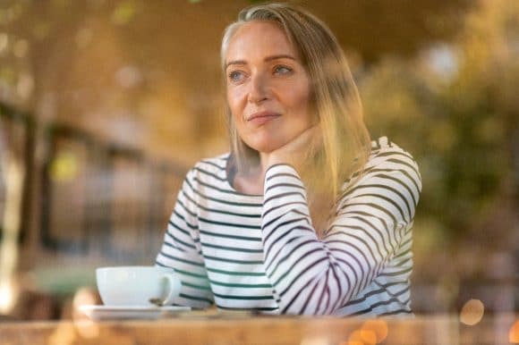 Woman drinking from a cup and looking out the window
