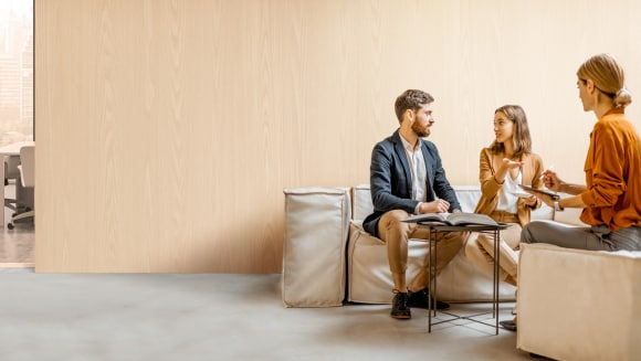 Un homme et une femme discutent de choix financiers avec un stratège dans un bureaux.