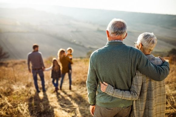 Des grands-parents regardent leur fille, leur gendre et leurs deux petits-enfants lors d’une randonnée en famille à la montagne.