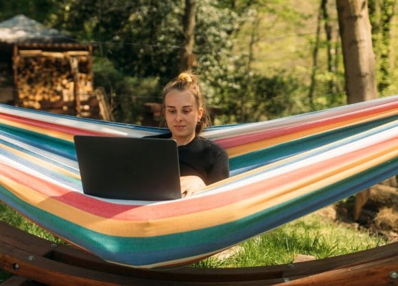 Ragazza in amaca che lavora sul computer portatile
