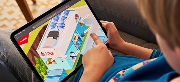 L’immagine mostra un ragazzo che, insieme ai suoi genitori, esplora la città virtuale SwissSkills City su un iPad.