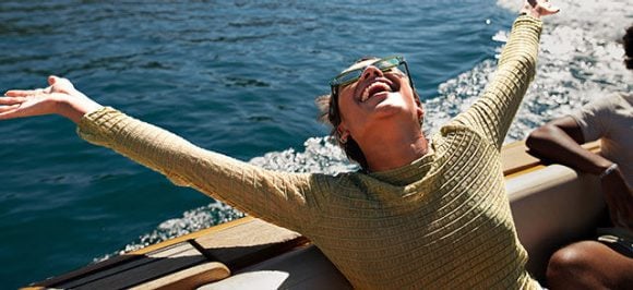 Das Bild zeigt eine glückliche Frau auf einem Boot.