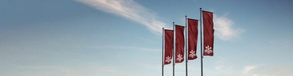 Four UBS flags wave against a clear blue sky.