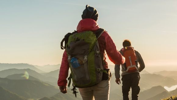 View of two people hiking in the mountains with the morning sun