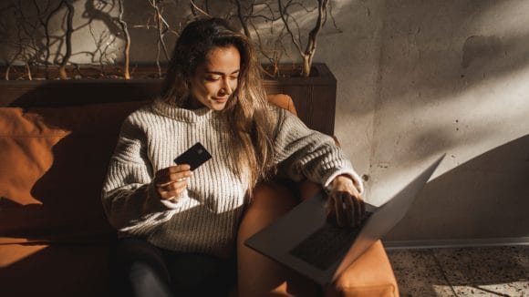 Woman holding credit card and laptop