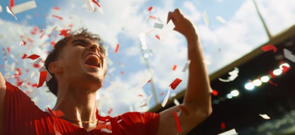 The picture shows a cheering young man with confetti in the sky.