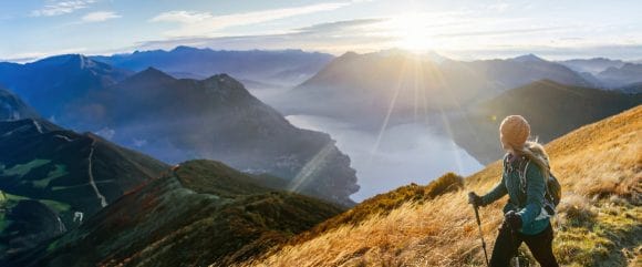 Woman hiking in the mountains, looking at the sun shining