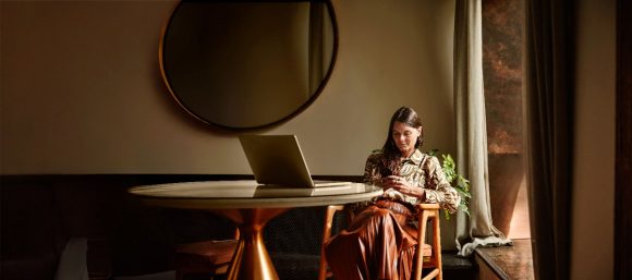 Women using her phone at a table with a laptop