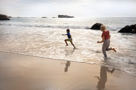 Grandmother with grandson running on beach