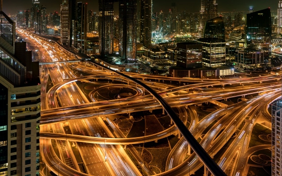 A high-angle, long-exposure photograph of a complex multi-level highway interchange at night