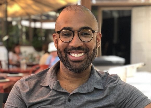 David Wilkes is looking and smiling directly to the camera