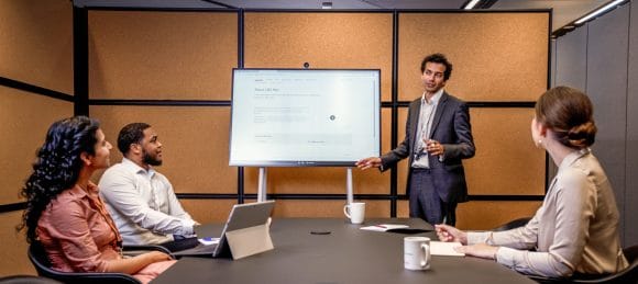 four people in a meeting, one of them presenting something