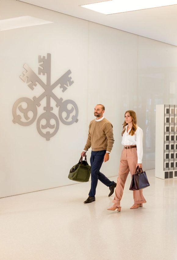 2 colleagues walking in the office next to the UBS 3 Keys logo 