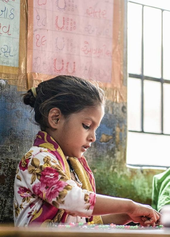 A girl plays at a table with colored balls.
