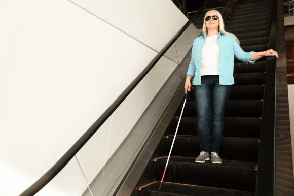 Young woman with prosthetic hand consulting work with her male colleague on computer monitor in the office.