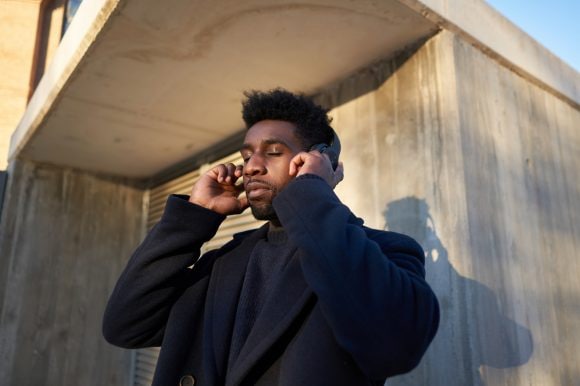 A young man listens to podcasts under a concrete corner