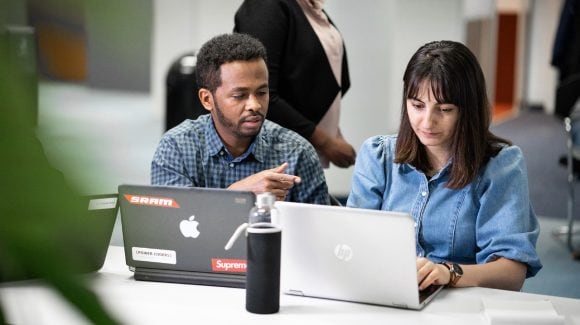 Two people using laptop