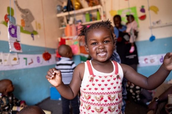 A young child smiling in a classroom