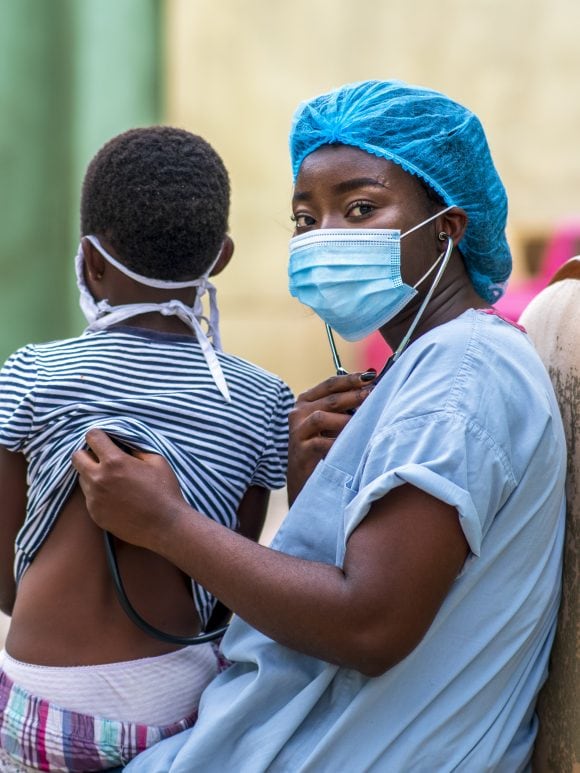 A female doctor visiting a child in a healthcare facility in Africa