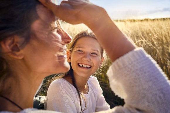 A mother and daughter smiling in a corn field