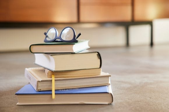 Glasses and pile of books on floor