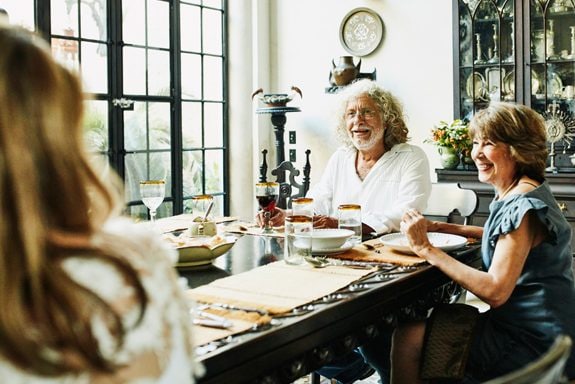 Smiling grandparents seated together at dining room table during dinner