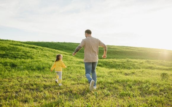 Father and daughter playing together on sunny day