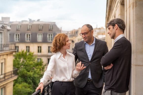 Three business people in a conversation outside on a rooftop gallery, Paris