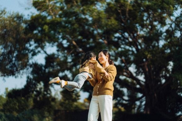 Mother spinning daughter around in park