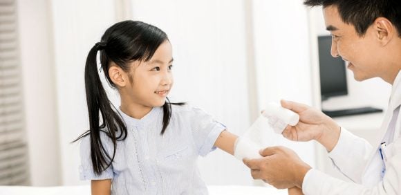 Un doctor vendando una herida para una niña