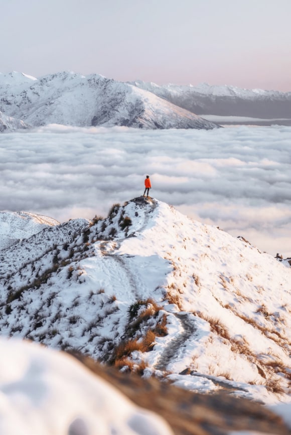 Un hombre en el pico de una montaña con nieve