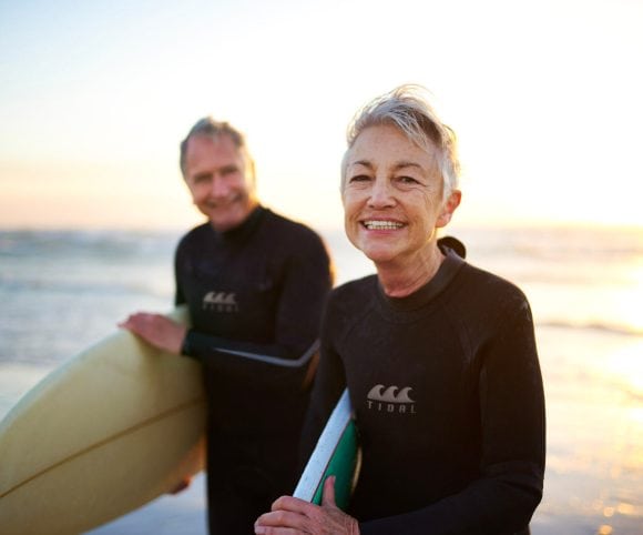 Pareja de adultos mayores regresando de surfear